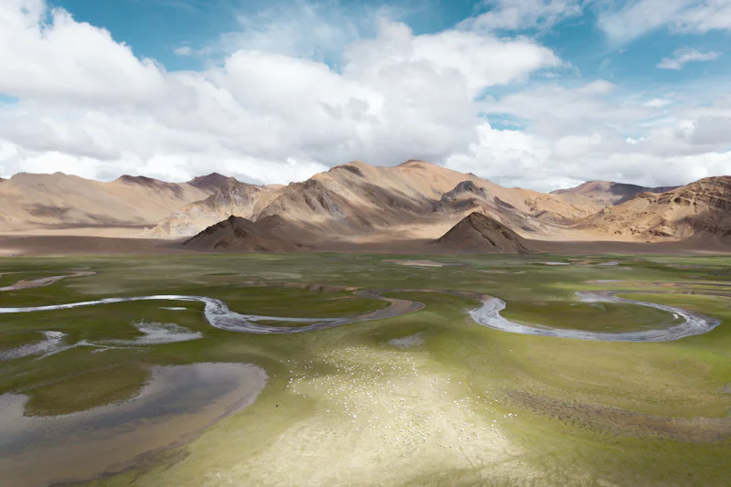 Aerial view of a braided river across a high plateau valley with arid peaks