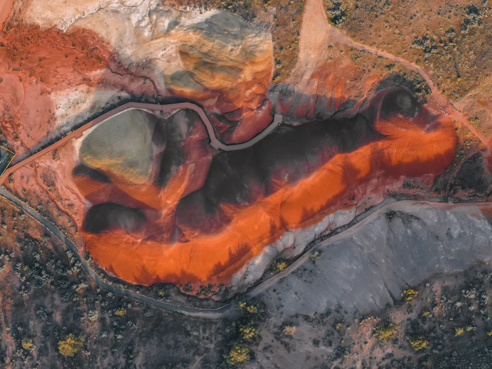 Top-down aerial view of a mine tailings area with haul road and ponds